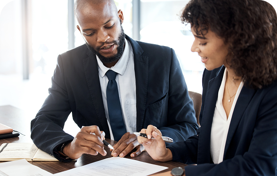 Two professionals reviewing documents together at desk.